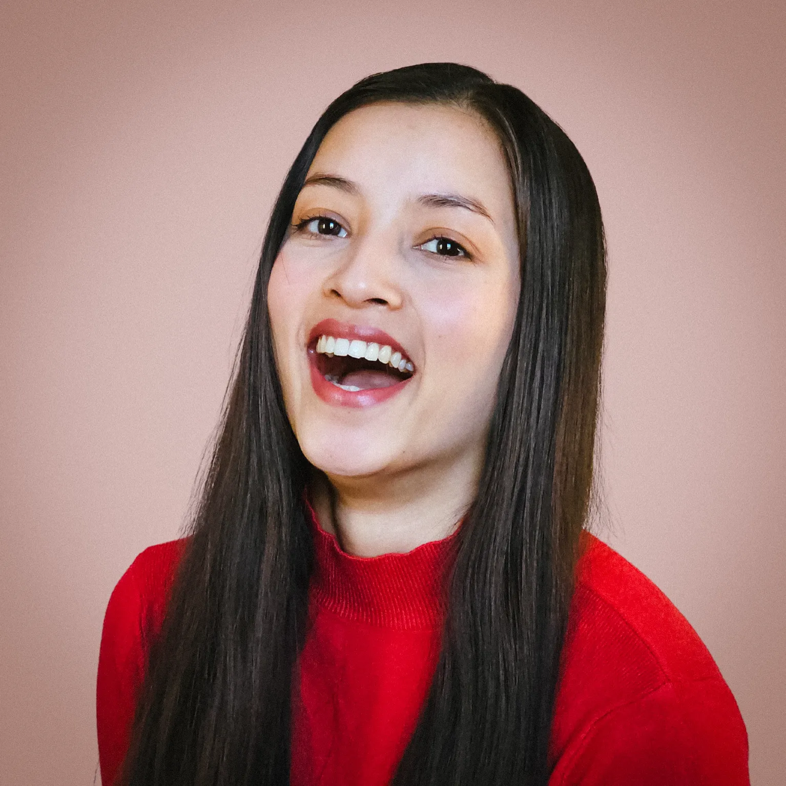 Diya Shrestha laughing, in a red sweater